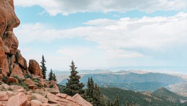 Rocky Colorado mountain overlook with trees and distant ridgelines