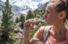 Hiker drinks from a hydration tube in a snowy mountain landscape
